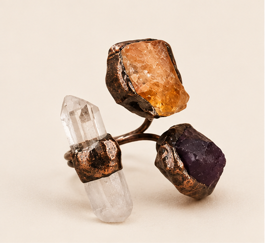 Amethyst, citrine, and clear quartz three stone ring on warm off-white, showing its open branch-like form.