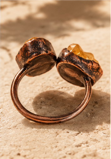 Side view of an open ring, showing the gap between the amethyst and citrine ends and the raised stone settings.
