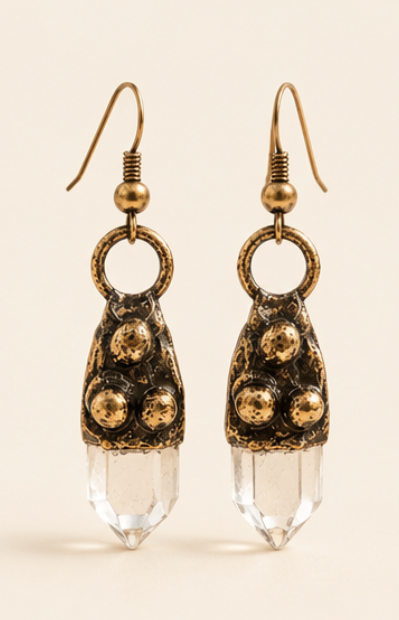 Pair of clear quartz crystal drop earrings on warm off-white, showing copper hooks, round links, and faceted points.