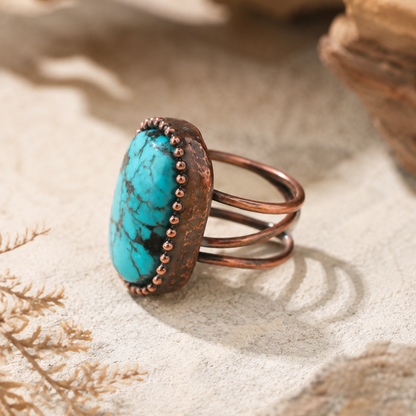 Turquoise ring styled on natural stone with warm neutral background and refined desert-inspired mood.