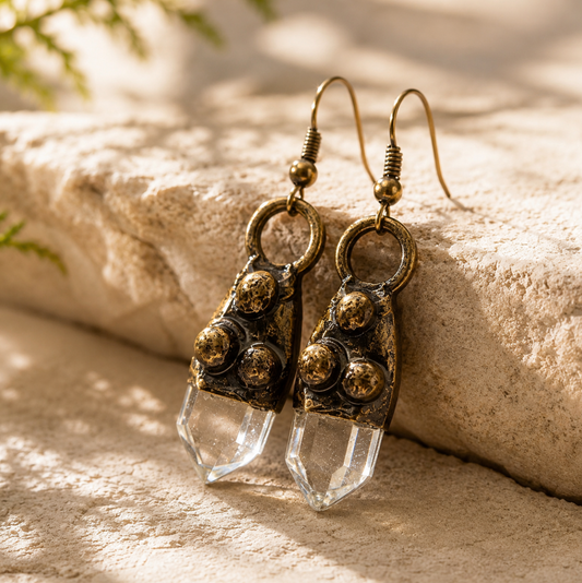 White crystal earrings displayed on soft fabric with clear quartz points and refined handcrafted texture.