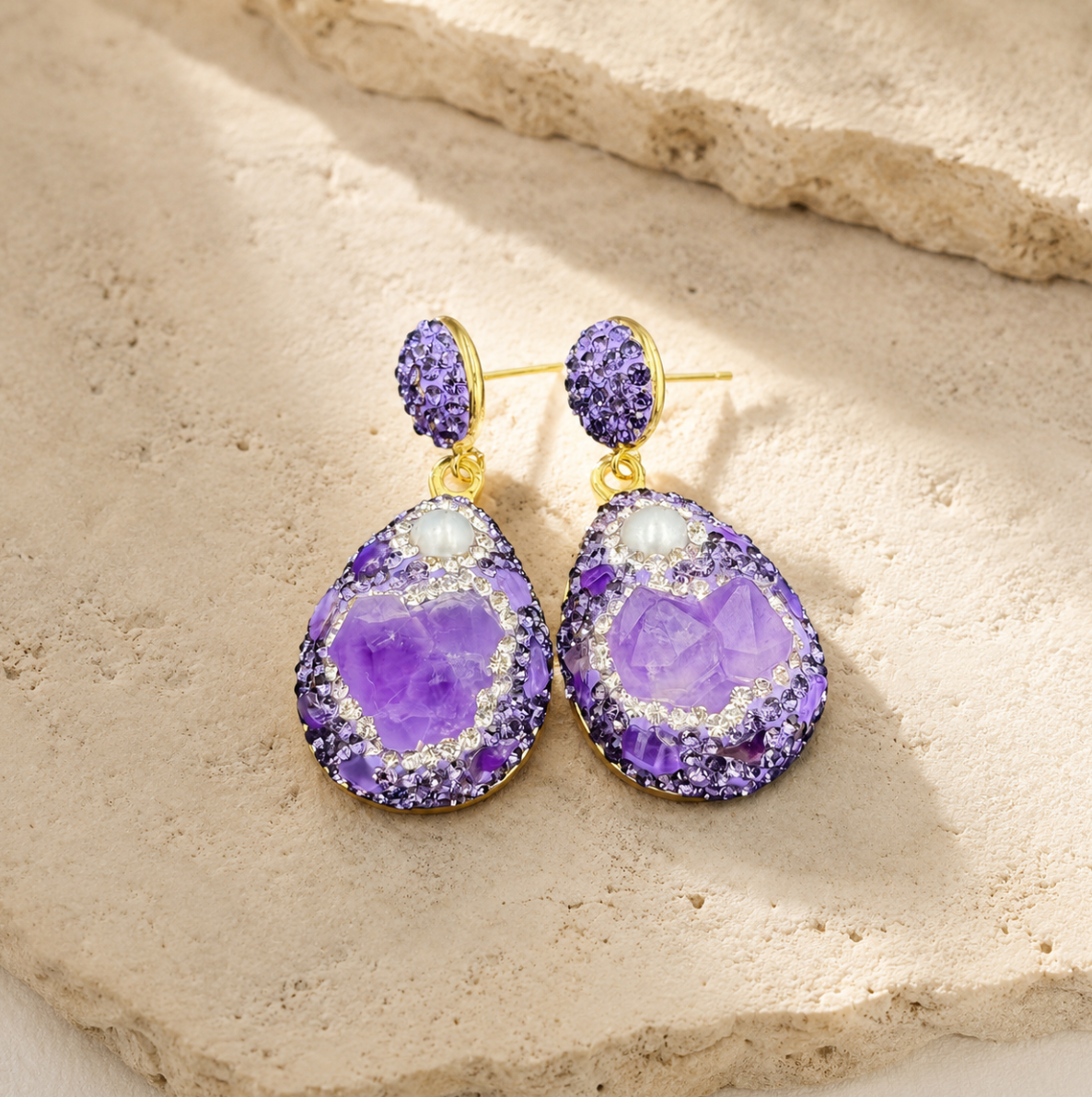 Amethyst earrings gold styled on a natural stone surface with warm light and refined luxury mood.