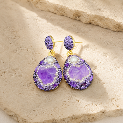 Amethyst earrings gold styled on a natural stone surface with warm light and refined luxury mood.