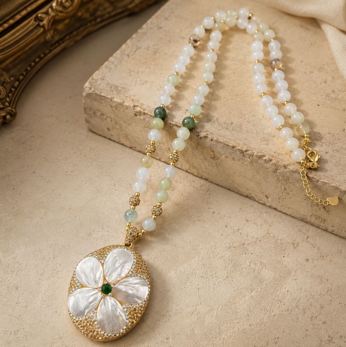 Pearl shell necklace with floral mother-of-pearl pendant, soft pearl beads, and green gemstone accent.