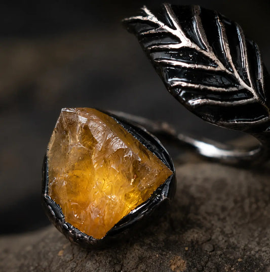 Citrine ring with feather shaped ring design, warm crystal texture, and quiet feminine mood.