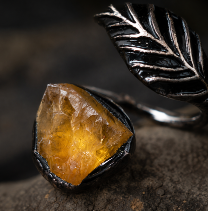 Citrine ring with feather shaped ring design, warm crystal texture, and quiet feminine mood.