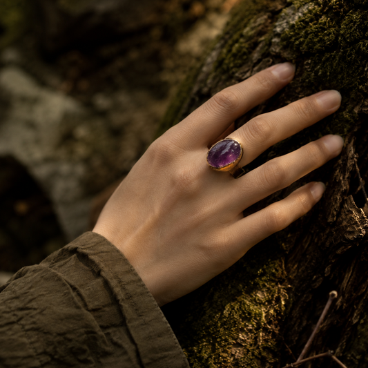 Amethyst ring styled on the hand with soft purple glow, natural texture, and refined everyday elegance.