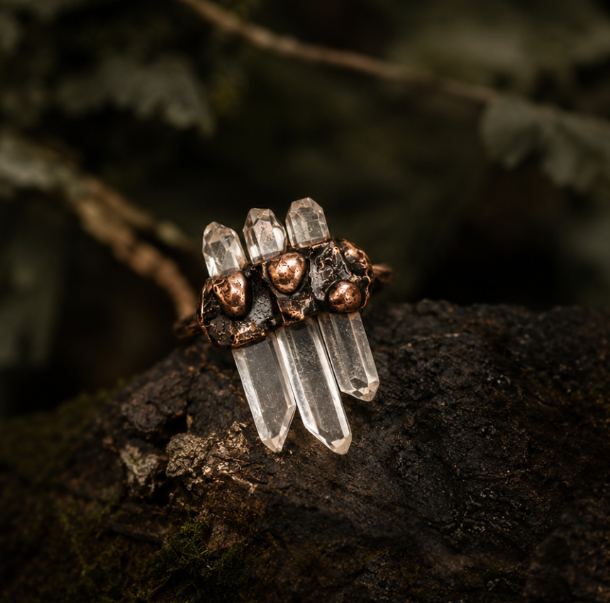 White crystal ring styled on natural stone with earthy moss, copper details, and clear quartz points.