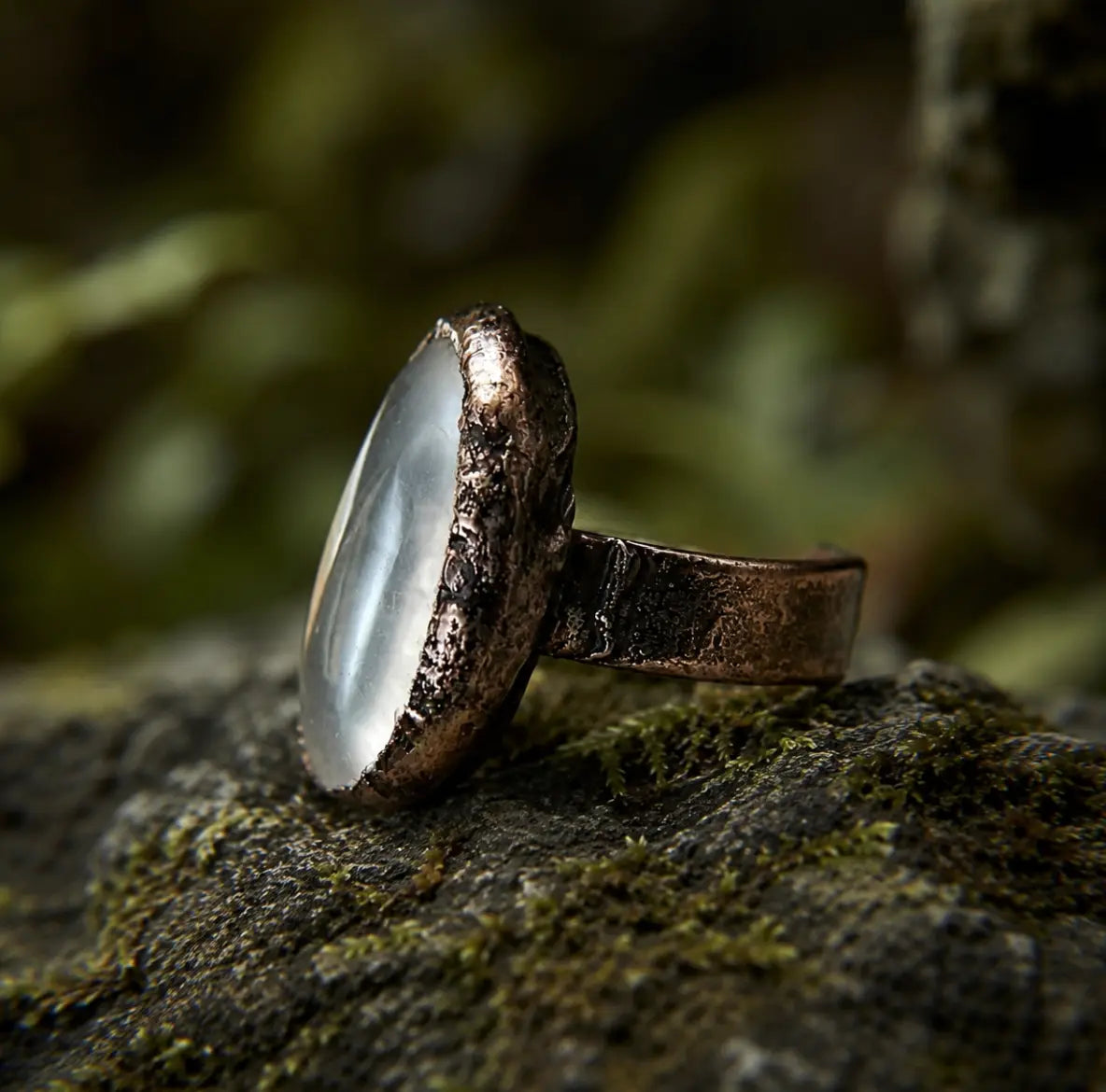 Clear quartz ring with polished translucent stone, organic edges, and dark vintage-toned setting.