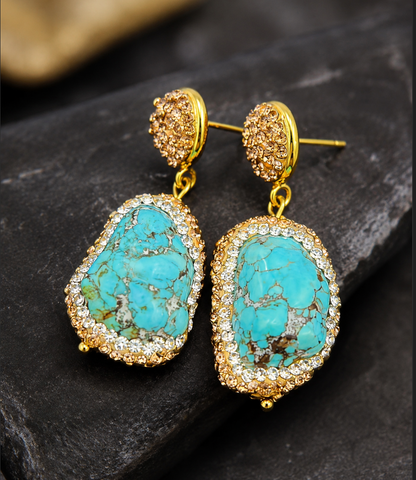 Turquoise drop earrings displayed on natural stone