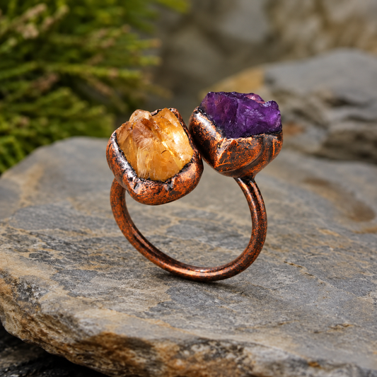 Amethyst and citrine two stone ring on warm off-white, showing the open band and contrasting purple and gold stones.