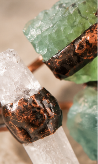 Side view of an open ring, showing the split band, clear quartz point, and two green fluorite stones.