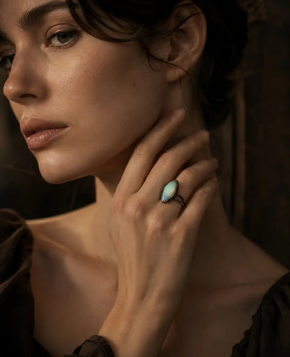 Rainbow moonstone ring styled on the hand with subtle blue-green sheen and quiet feminine mood.
