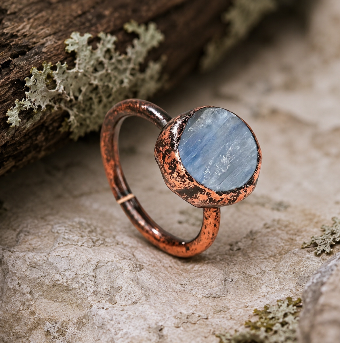 Flat gemstone ring featuring a disc shape ring silhouette, blue crystal surface, and earthy metal detail.