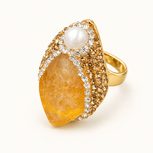Front three-quarter view of a citrine ring with a honey-yellow stone, pearl accent, and polished gold-tone band